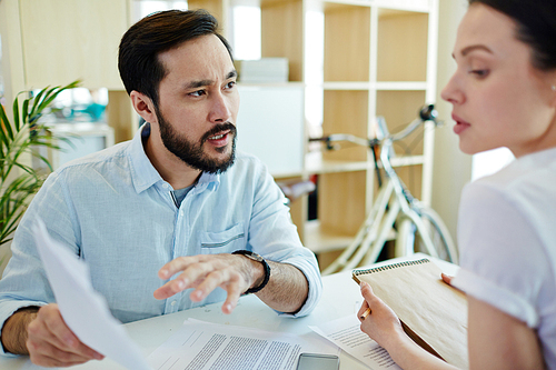 Portrait of two tense business people having discussion of work during meeting in modern creative office space