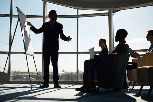 Confident man pointing at blank whiteboard at seminar