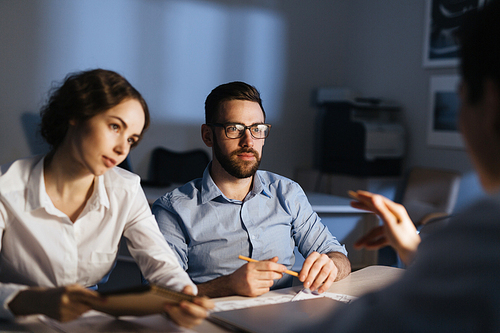 Group of co-workers having discussion in late evening in office