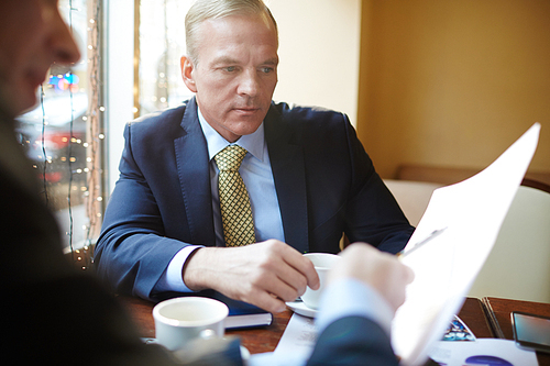 Serious banker listening to colleague explaining terms of new contract