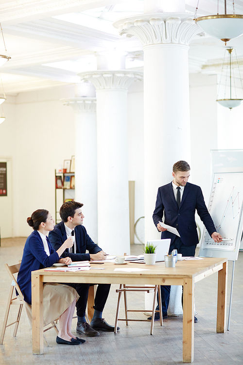 Businessman explaining graphical data or statistics on whiteboard to his colleagues