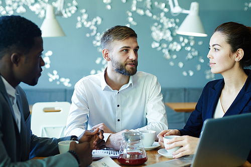 Two businessman and businesswoman discussing sales in cafe