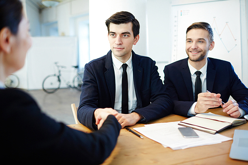 Young man handshaking with female after discussing contract terms