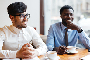 Happy employee and his colleague having talk with one of partners at coffee-break