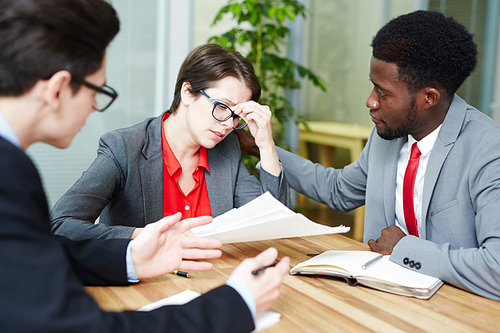 Businesswoman unable to concentrate whle reading financial papers at meeting with colleagues