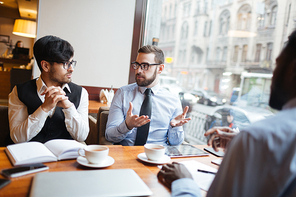 Group of young men having business discussion in cafe