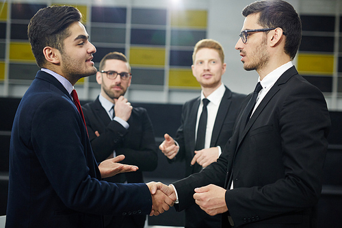 Confident businessmen handshaking after meeting