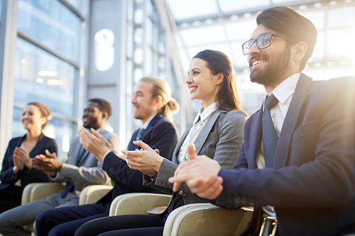 Contemporary business people clapping their hands at conference or other corporate event