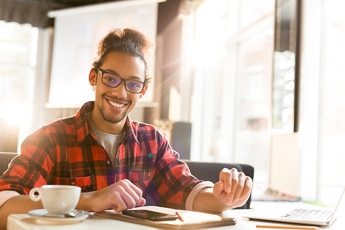 Young attractive man in eyeglasses spending time in cafe after college