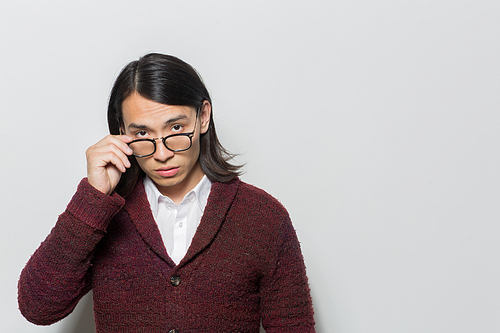 Strict young man taking off his eyeglasses while staring at camera