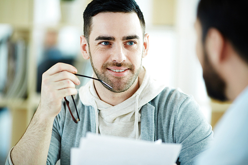 Portrait of handsome middle-aged man smiling listening to partner during meeting while discussing work in office