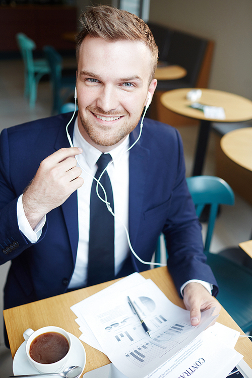 Young economist with documents and earphones 