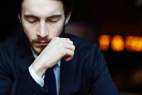 Head and shoulders portrait of handsome bearded man wearing elegant business suit, thinking with closed eyes