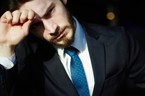 Head and shoulders portrait of handsome bearded man wearing elegant business suit,  in bright sunlight