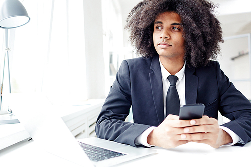 Pensive man in suit texting in smartphone during work in office