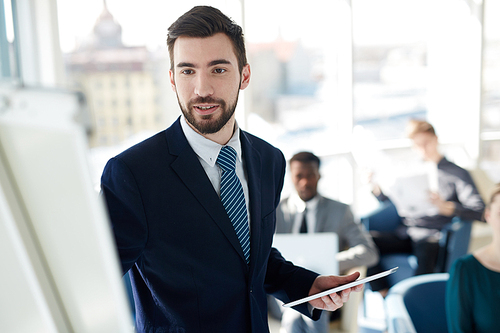 Portrait of handsome successful businessman standing at whiteboard during presentation meeting