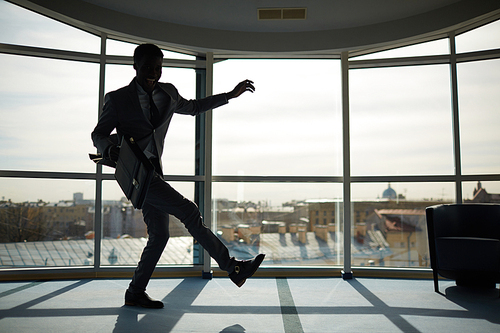 Energetic businessman with briefcase dancing indoors