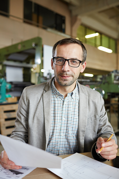 Successful engineer in formalwear and eyeglasses  while working with papers