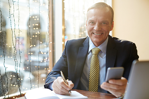 Smiling banker sitting in cafe and planning his work