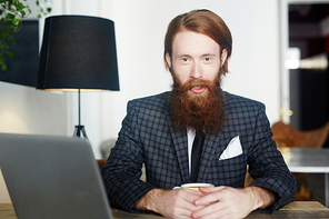 Bearded employer with cup of tea sitting in cafe