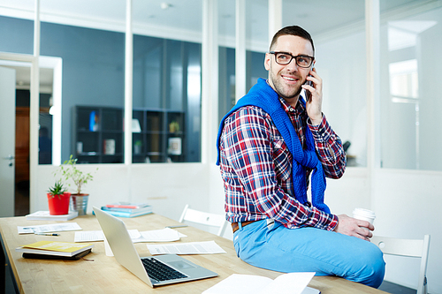 Smiling man in casualwear calling in office