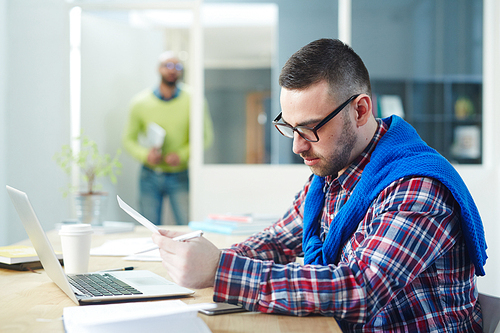 Young manager in casualwear reading papers in office