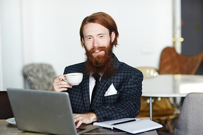 Classy businessman with cup of tea networking in cafe