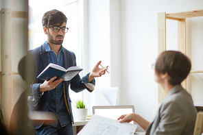 Portrait of two employees talking in office: successful project manager giving instructions to colleague discussing architectural plans