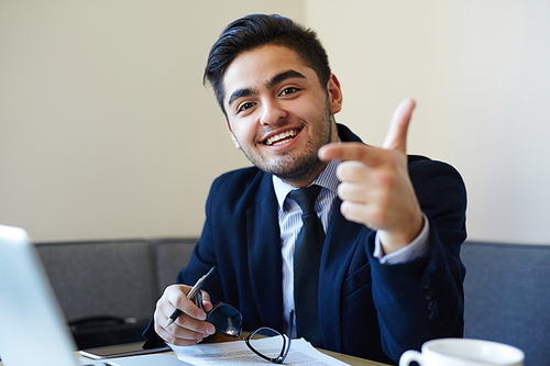 Successful salesman pointing at you from workplace