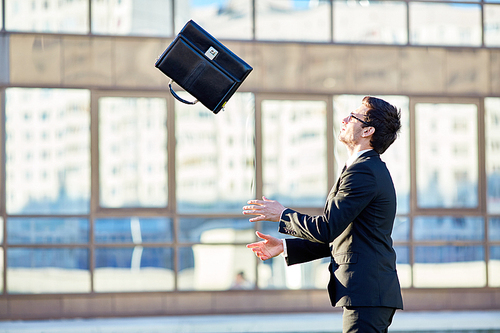 Young ambitious businessman throwing briefcase