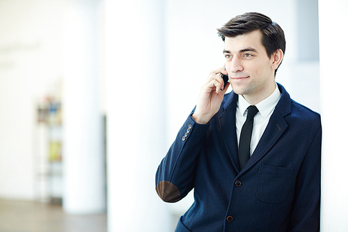 Confident young man in suit speaking on mobile phone