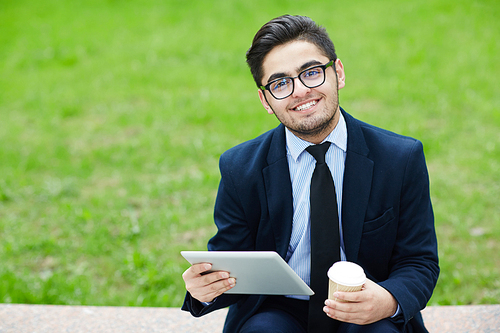 Businessman with gadget and drink 