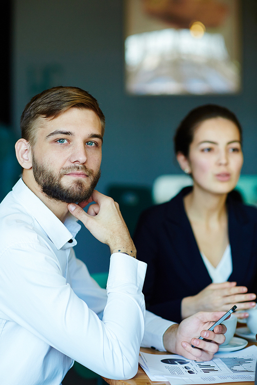 Portrait of young successful businessman looking away daydreaming during meeting in office