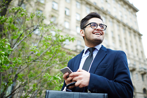 Smiling professional with smartphone walking in the city