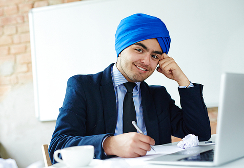 Successful Arabian businessman making notes while networking