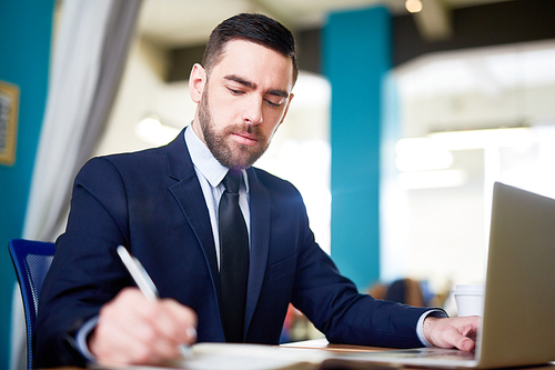 Serious trader making notes in notebook