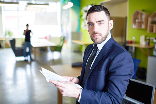 Contemporary businessman with documents working in office