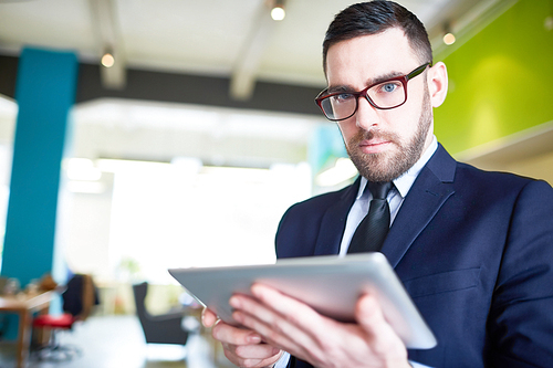 Confident trader with touchpad looking through online data