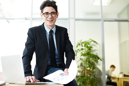 Young successful financier with papers working in office