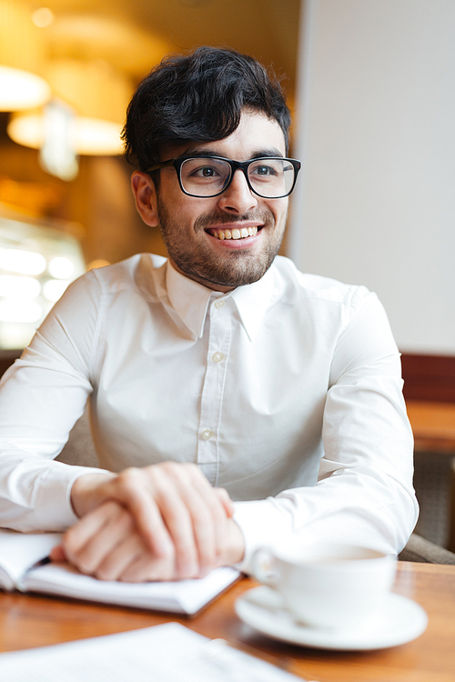 Happy young business leader having tea in cafe