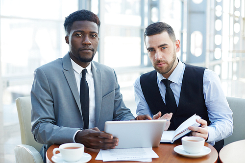 Portrait of two contemporary business people, one of them African-American,  during meeting in futuristic office building