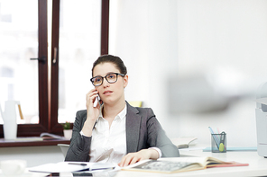 Young secretary or office manager speaking on the phone during working day