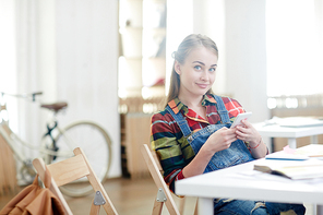 Cute student with smartphone messaging between lessons