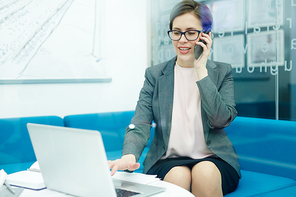 Young businesswoman talking by smartphone while networking