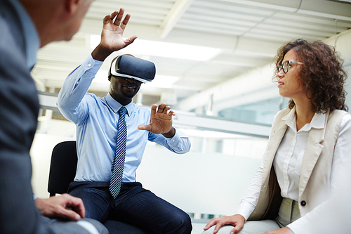Colleagues looking at businessman with vr headset taking part in virtual conference or webinar