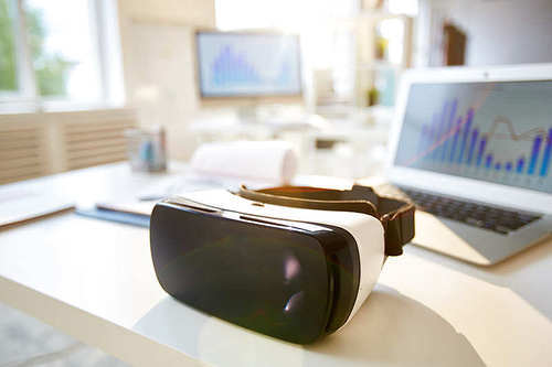 Virtual reality goggles on desk with laptop near by