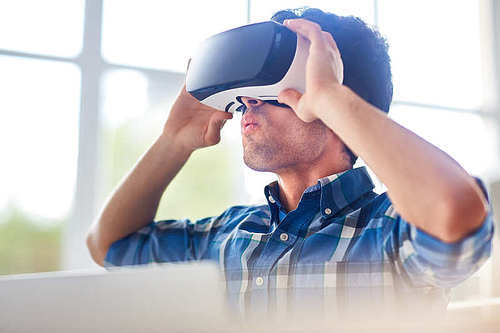 Young man with goggles having curious experience in virtual reality