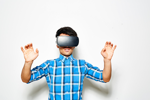 Bearded young men in checked shirt testing virtual reality goggles while standing against white background
