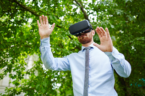 Portrait of man wearing VR headset experiencing nature walking in forest in real world