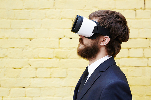 Side-view of young modern businessman watching video in vr headset
